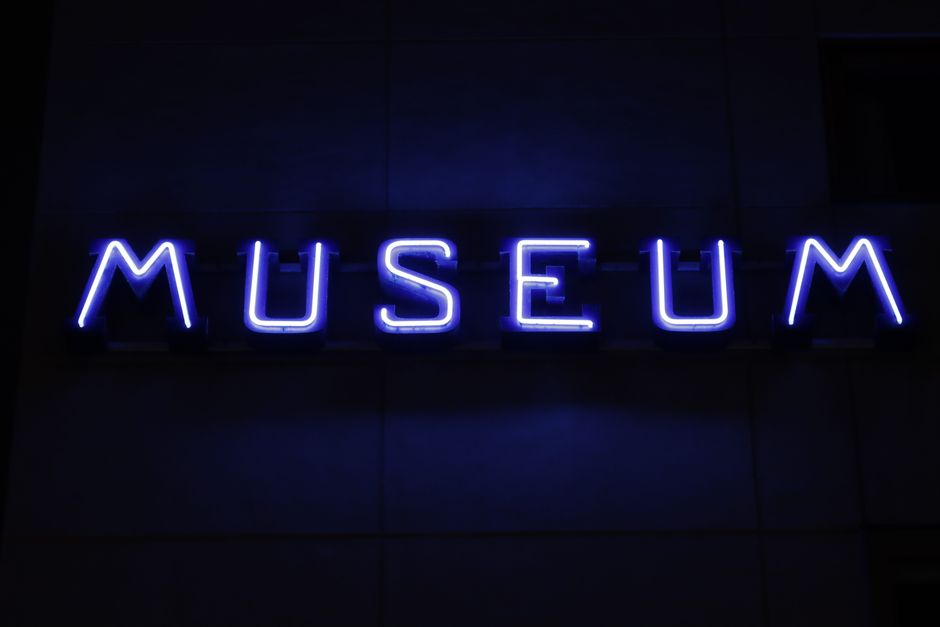 Bright blue neon sign spelling 'MUSEUM' against a dark wall in Jönköping, Sweden.