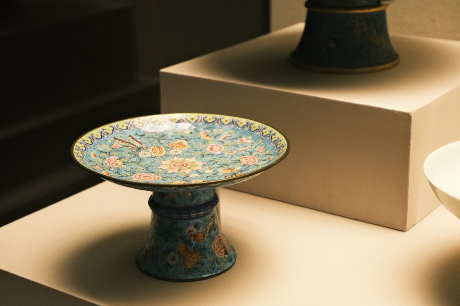 Beautiful ornate porcelain plate with intricate floral design on display in a museum.